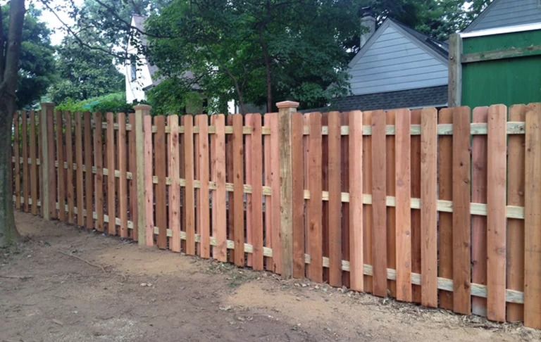 A wooden fence with a green garage in the background