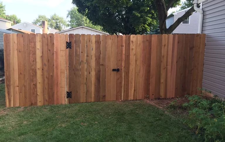 A wooden fence with a gate in the backyard of a house.