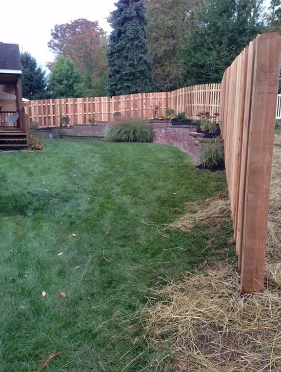 A wooden fence surrounds a lush green yard