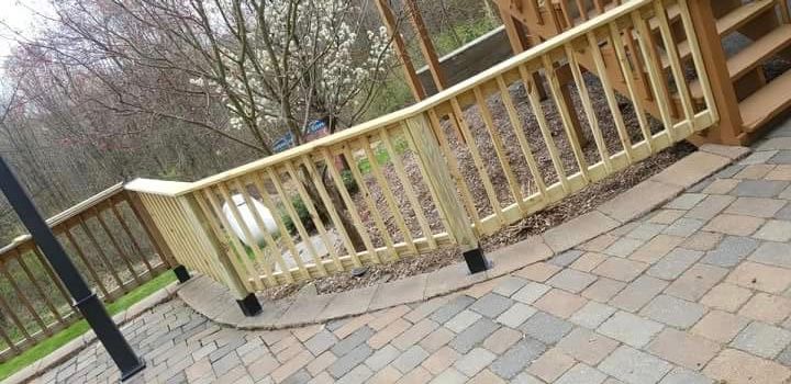 A wooden railing is sitting on top of a brick patio.