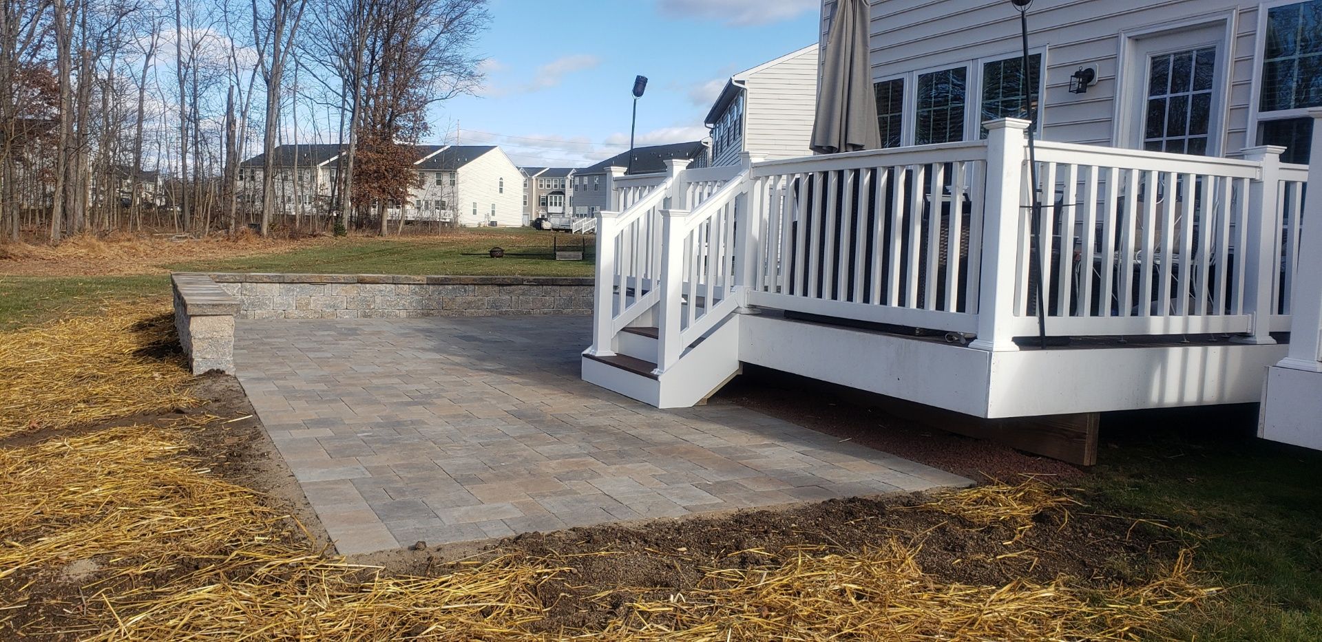 A white deck with stairs leading up to it is in the backyard of a house.