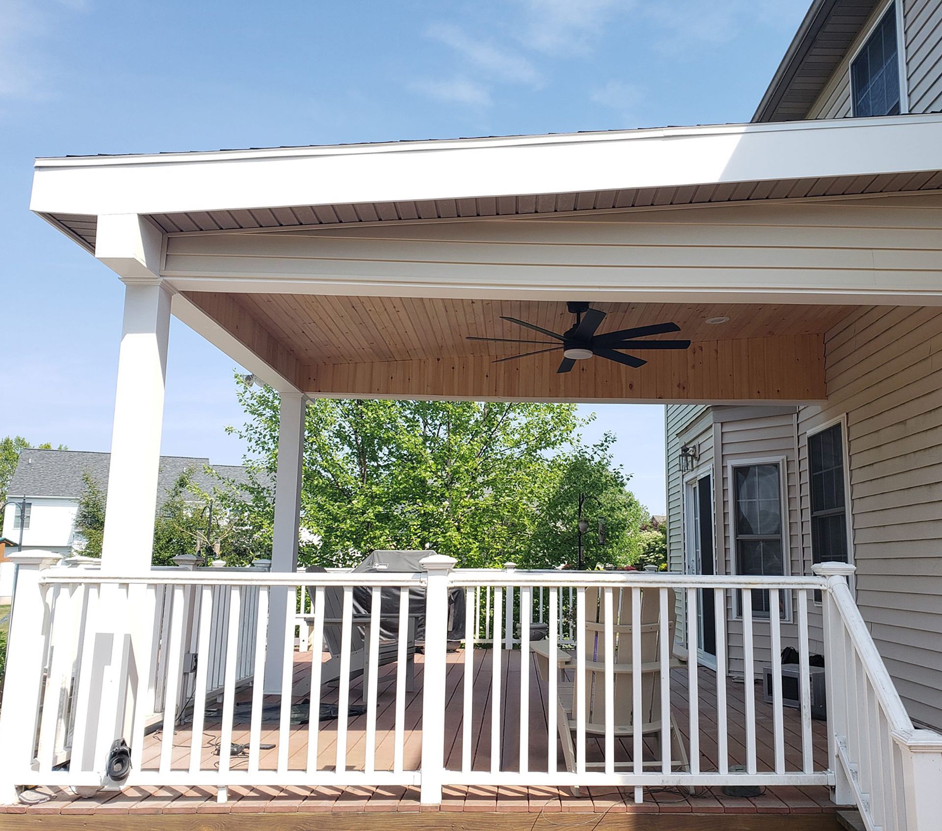 A porch with a ceiling fan and a white railing