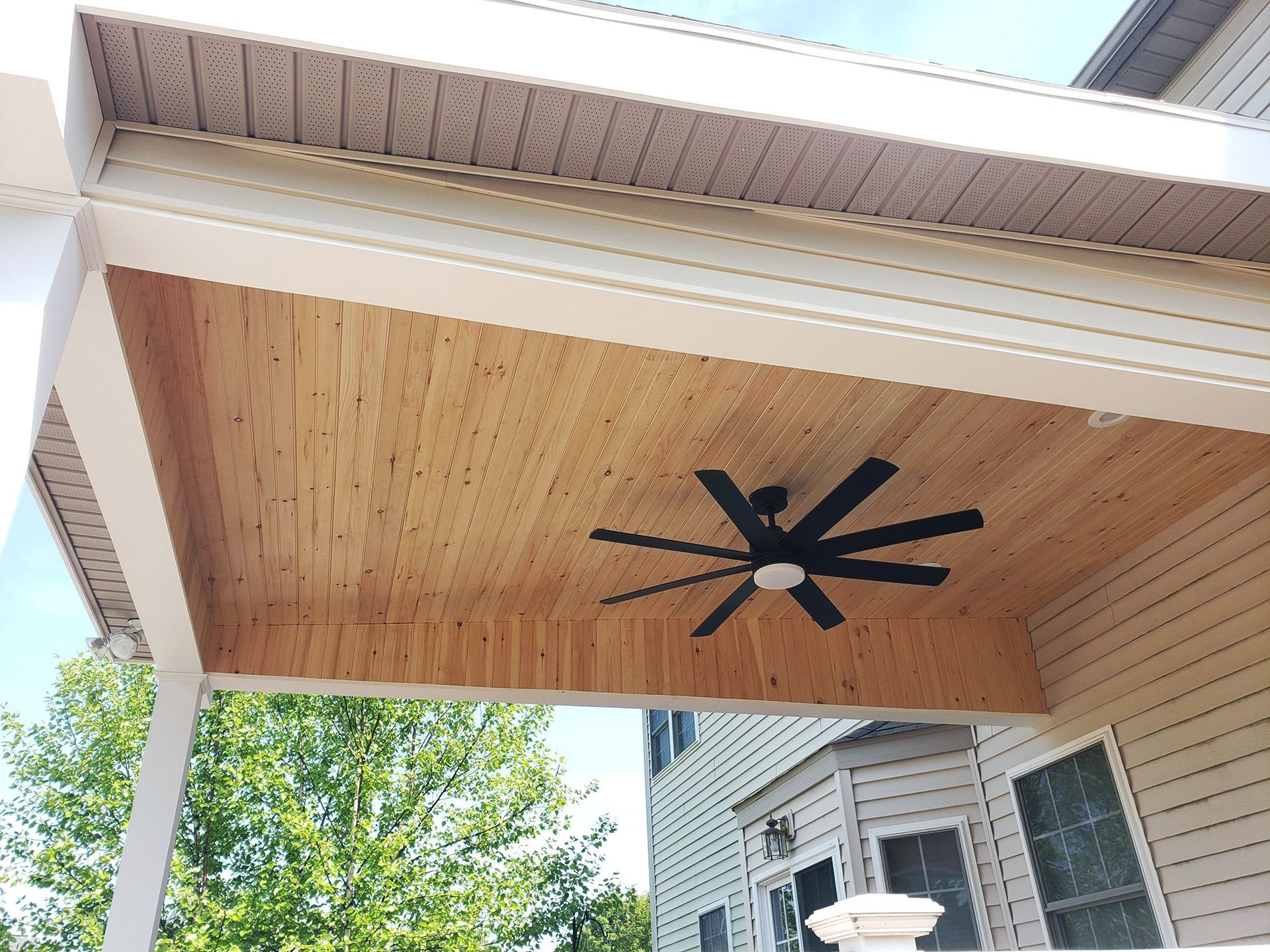 A ceiling fan is hanging from the ceiling of a porch.
