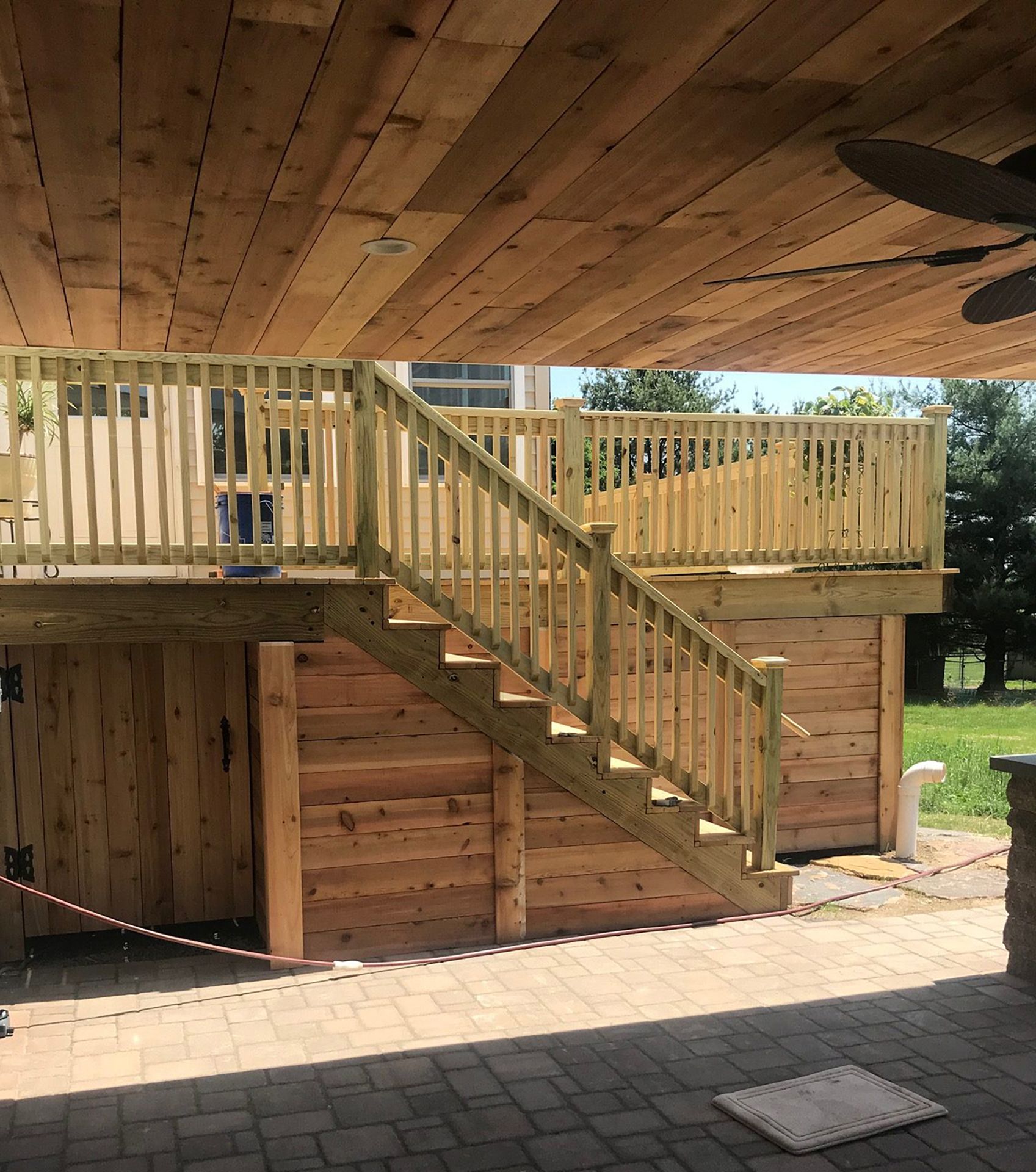 A wooden deck with stairs and a ceiling fan