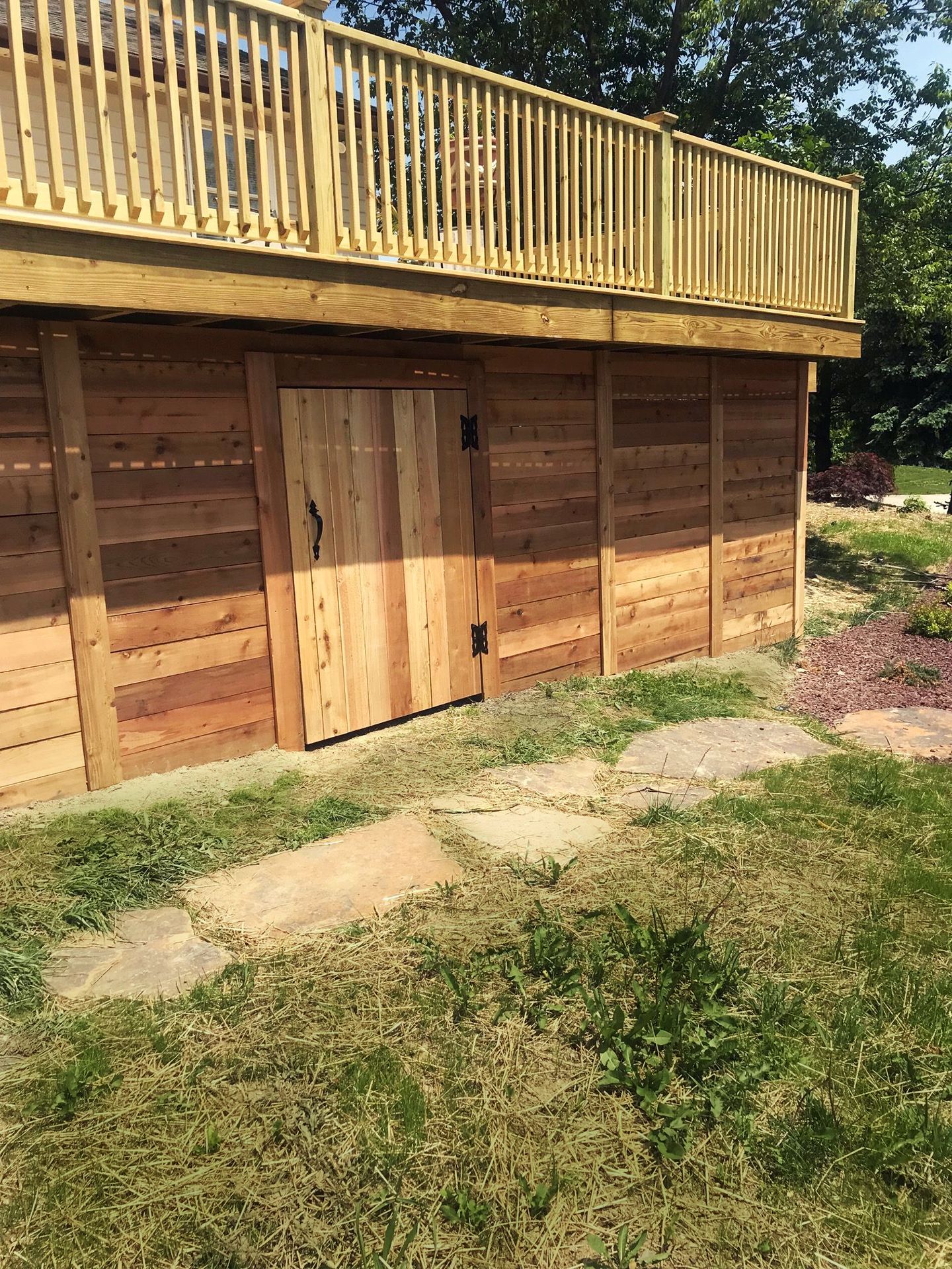 A wooden garage with a deck on top of it.