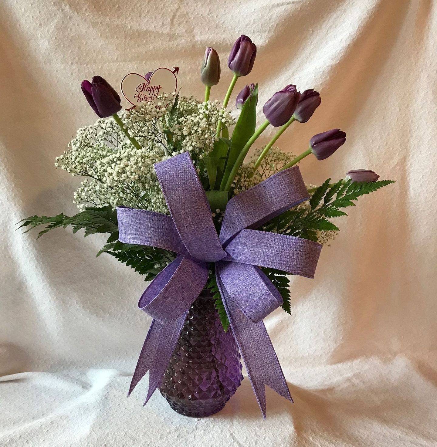 Purple flowers in a purple vase with a purple bow