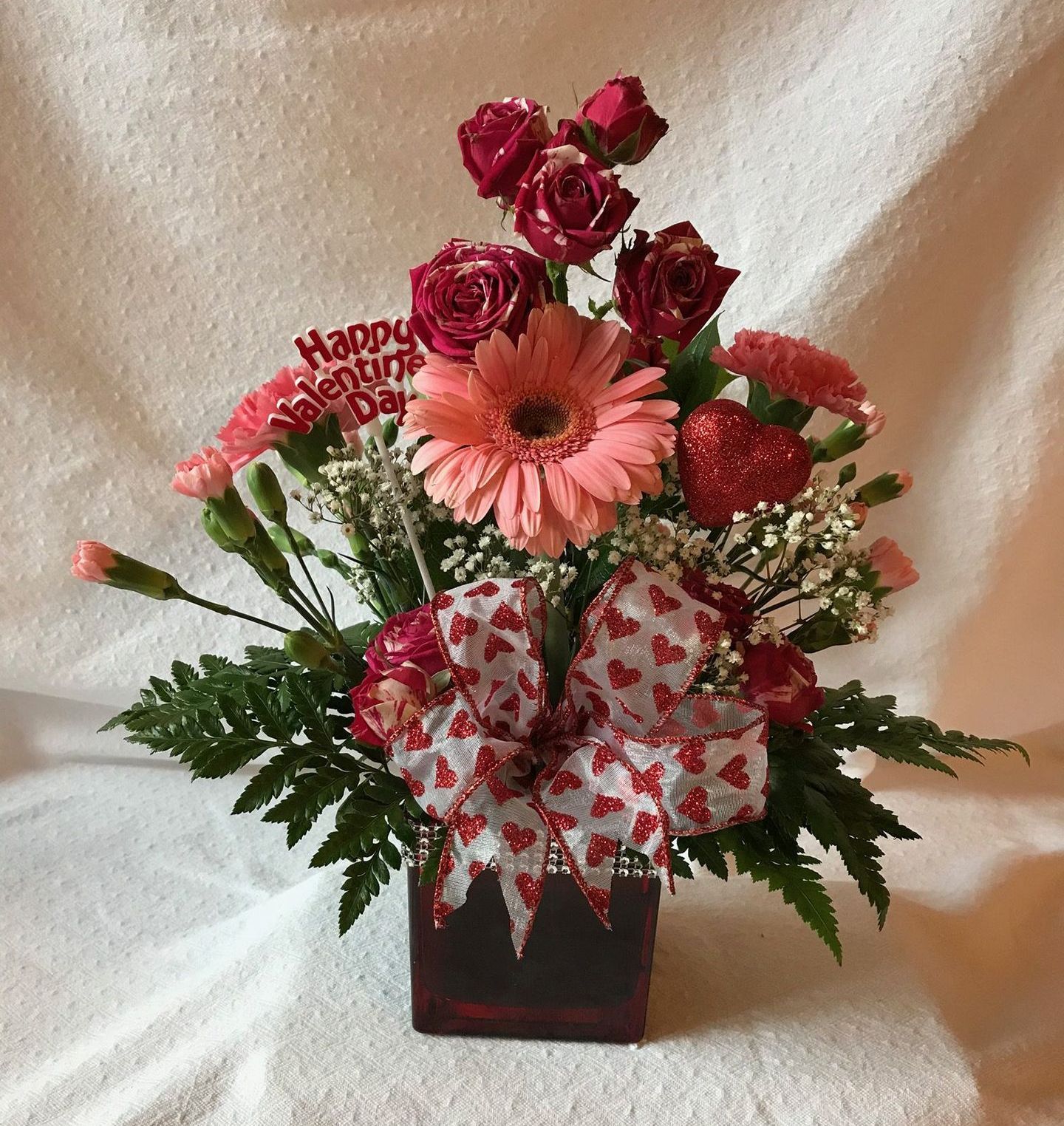 A vase filled with pink flowers and a happy valentine 's day sign