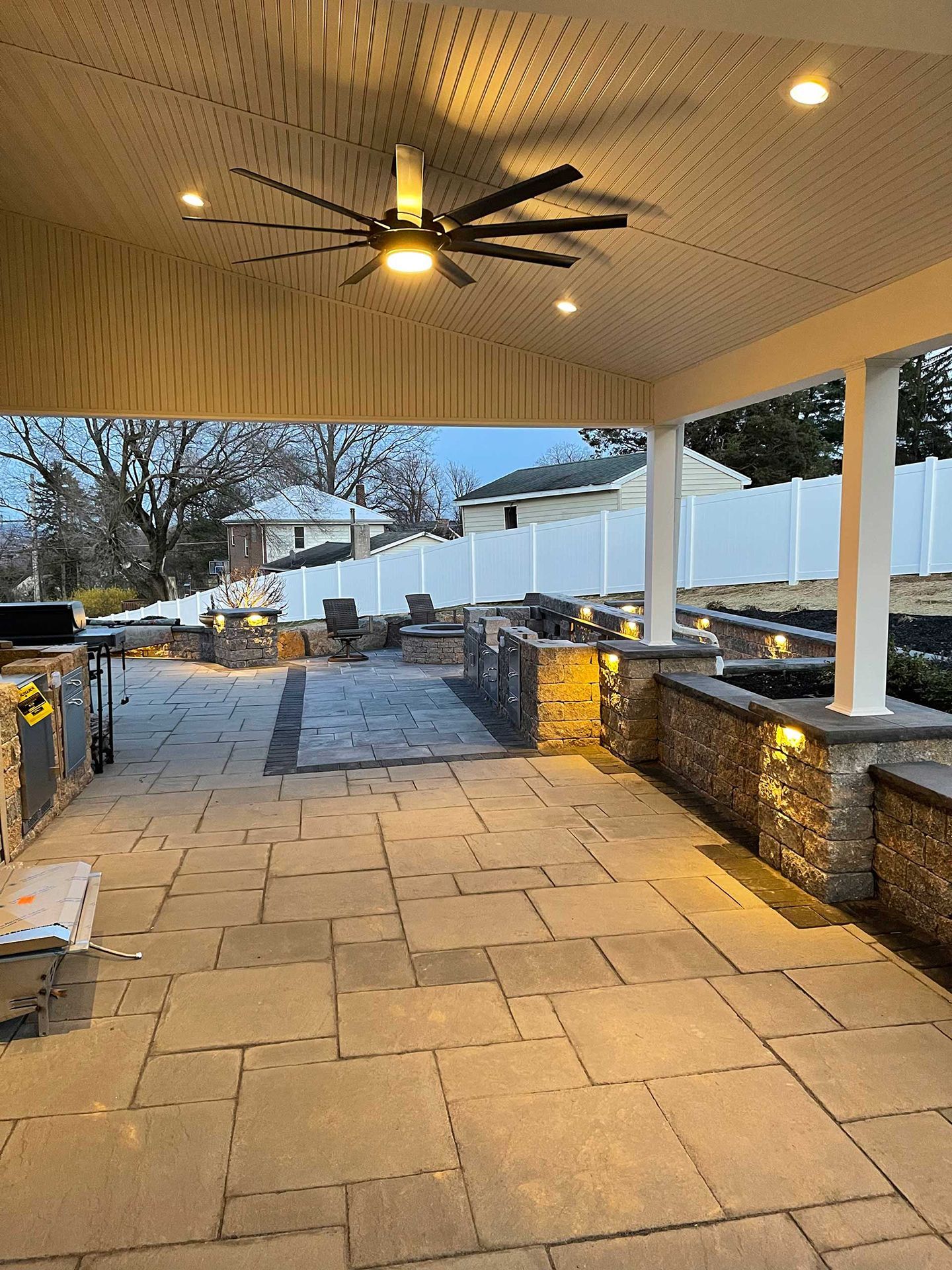 A patio with a ceiling fan and lights on it.