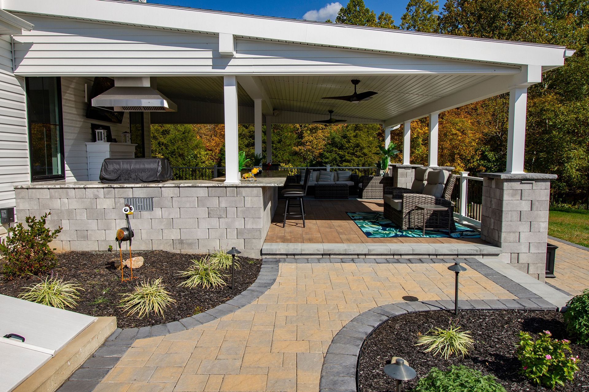 A large covered patio with a grill and a ceiling fan.