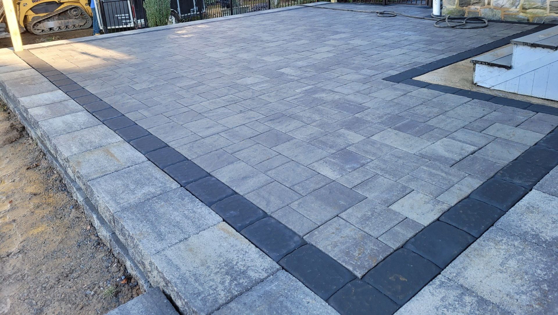 A brick driveway with a black border is being built.