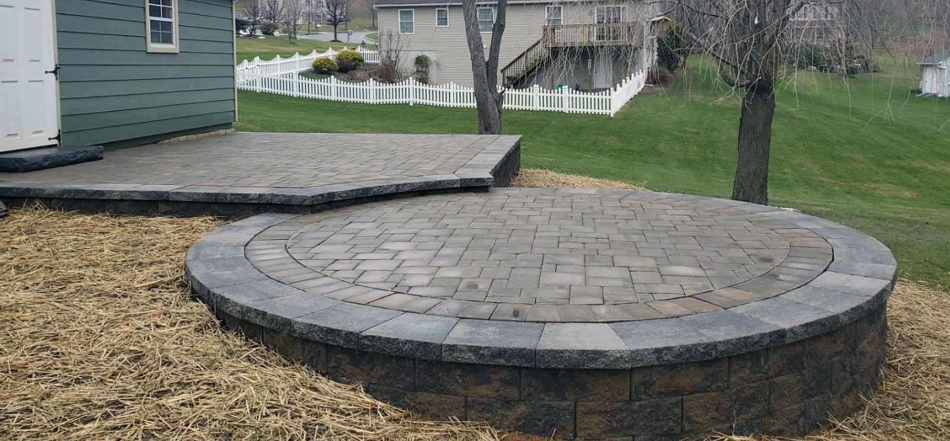 A circular brick patio with a shed in the background