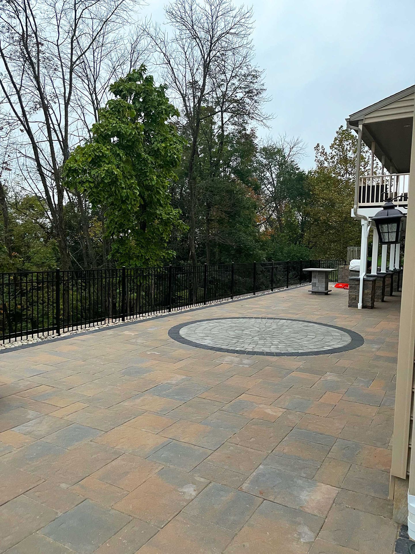 A large patio with a circular design in the middle of it surrounded by trees.
