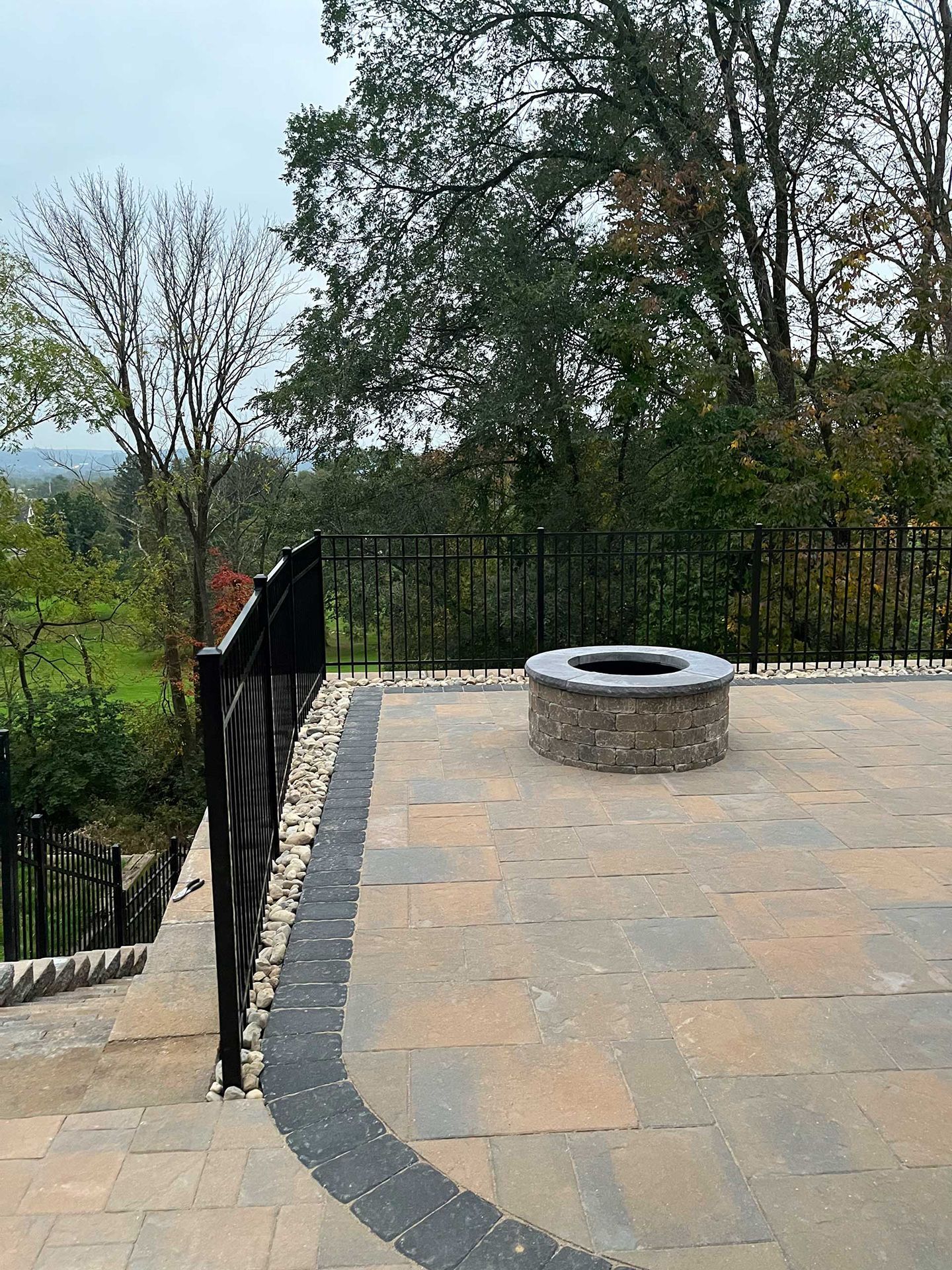 A fire pit is sitting on top of a patio next to a railing.