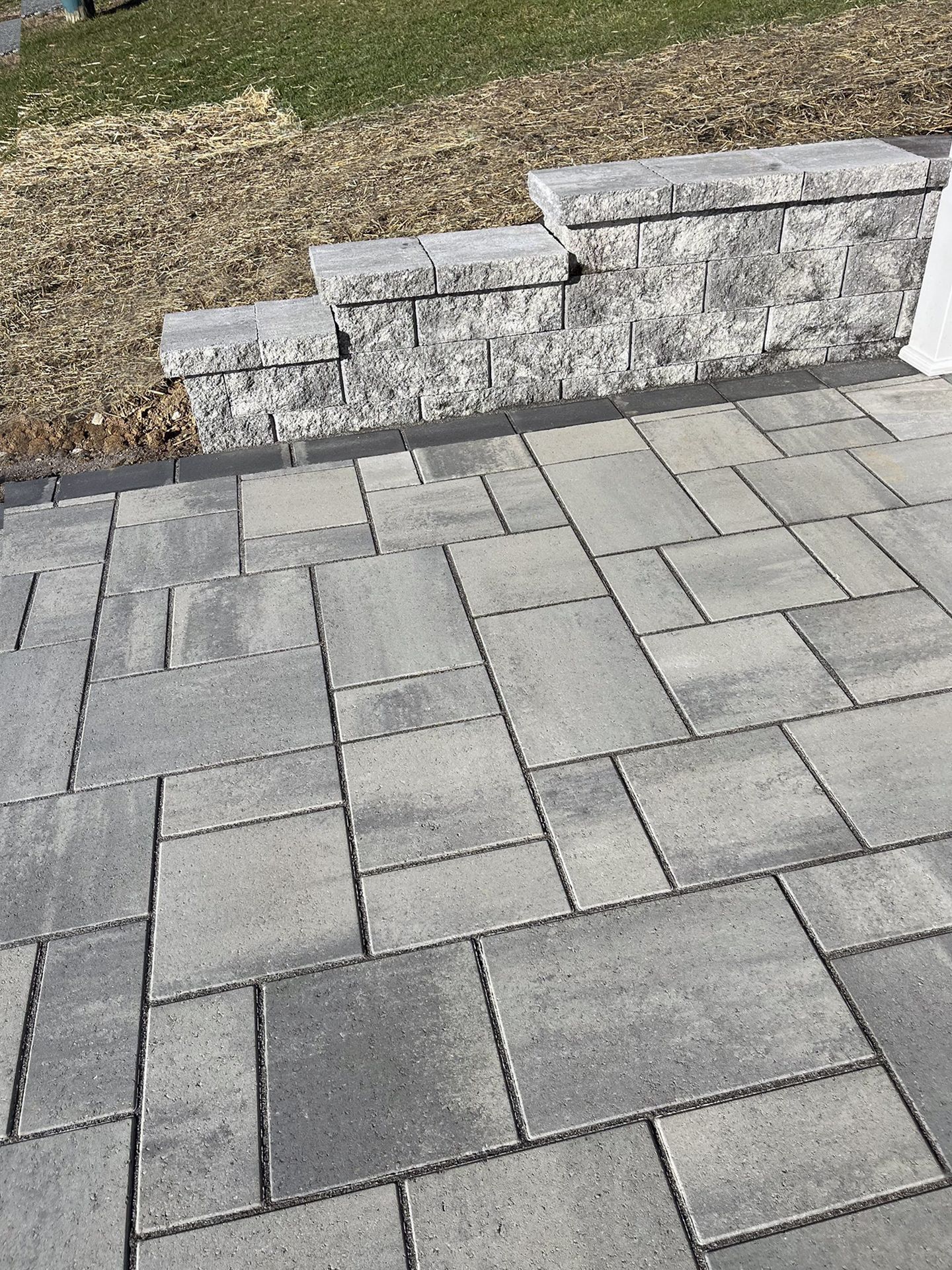 A brick walkway with a stone wall in the background.