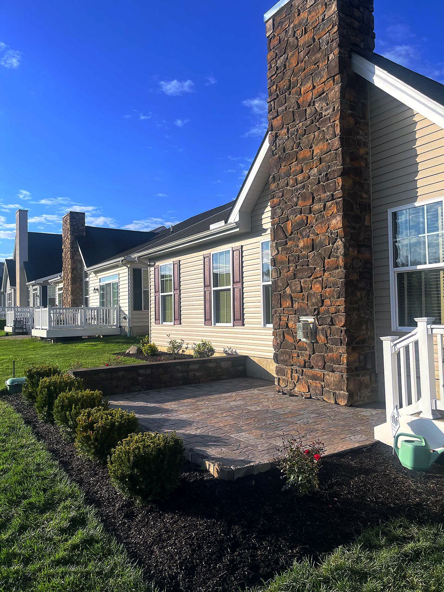 A house with a stone chimney and a patio in front of it.