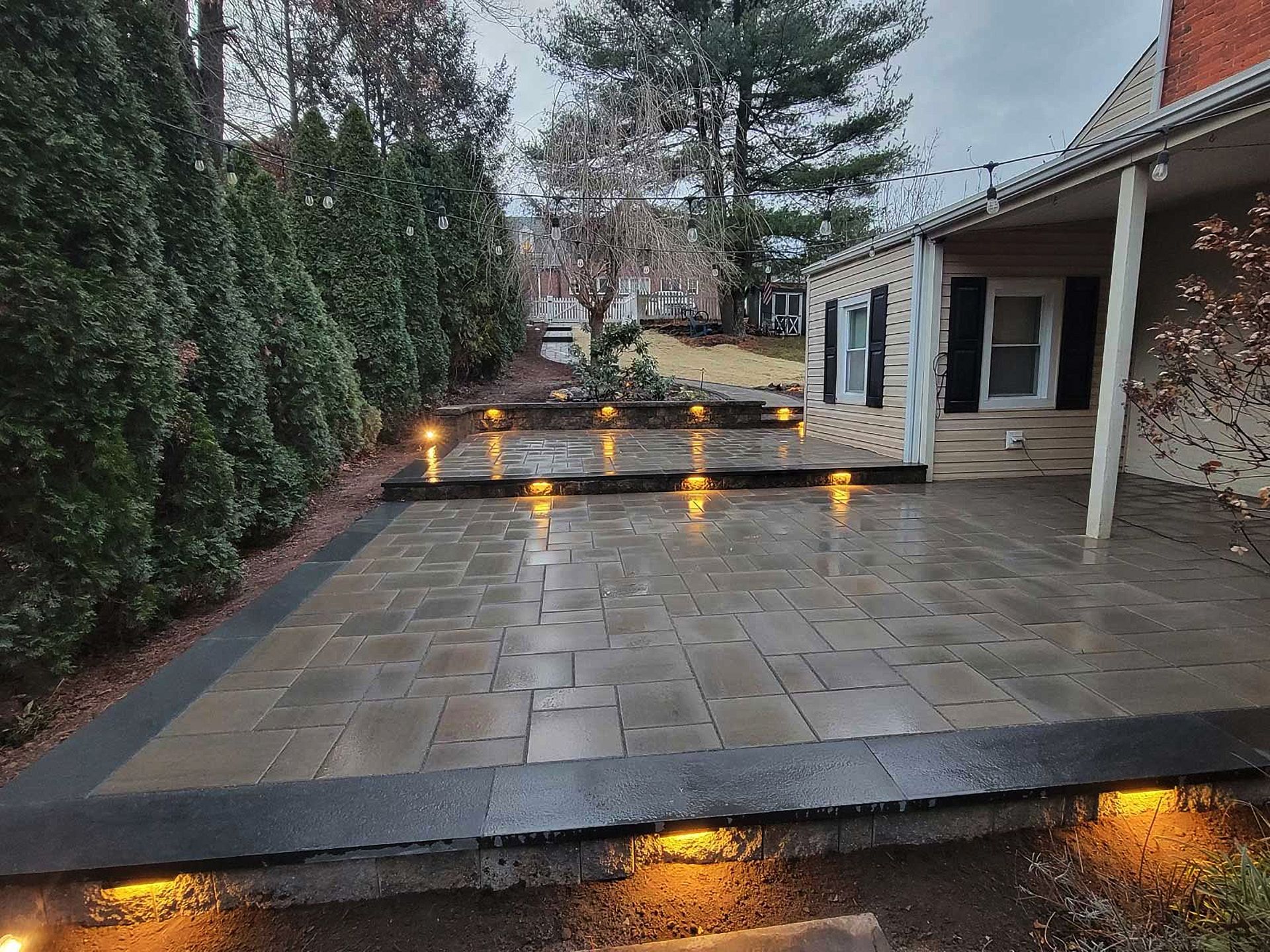 A patio with lights on it is in front of a house.