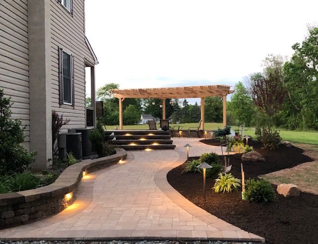 A walkway leading to a patio with a pergola and stairs.