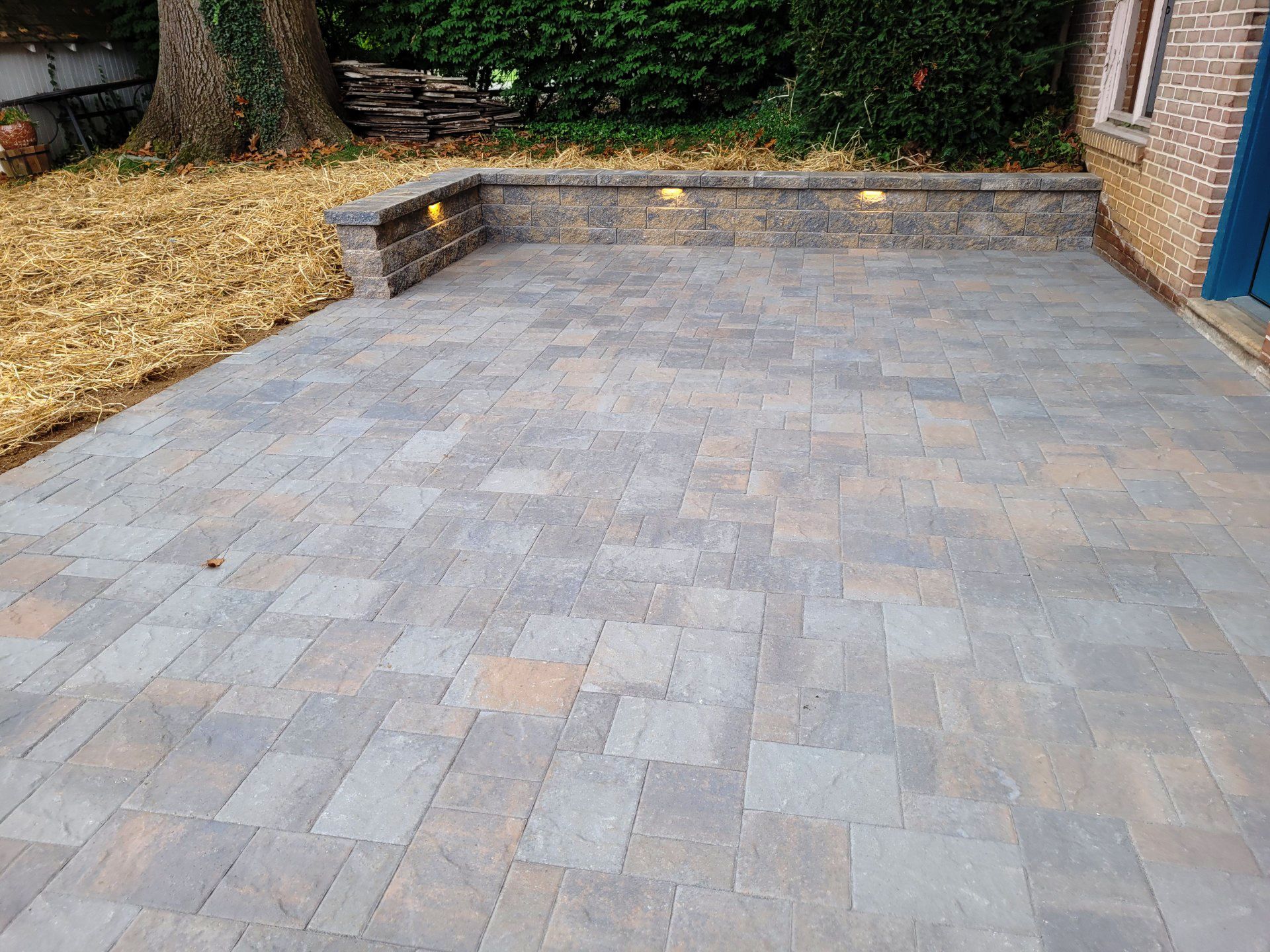 A patio with bricks and a stone wall in front of a brick house.