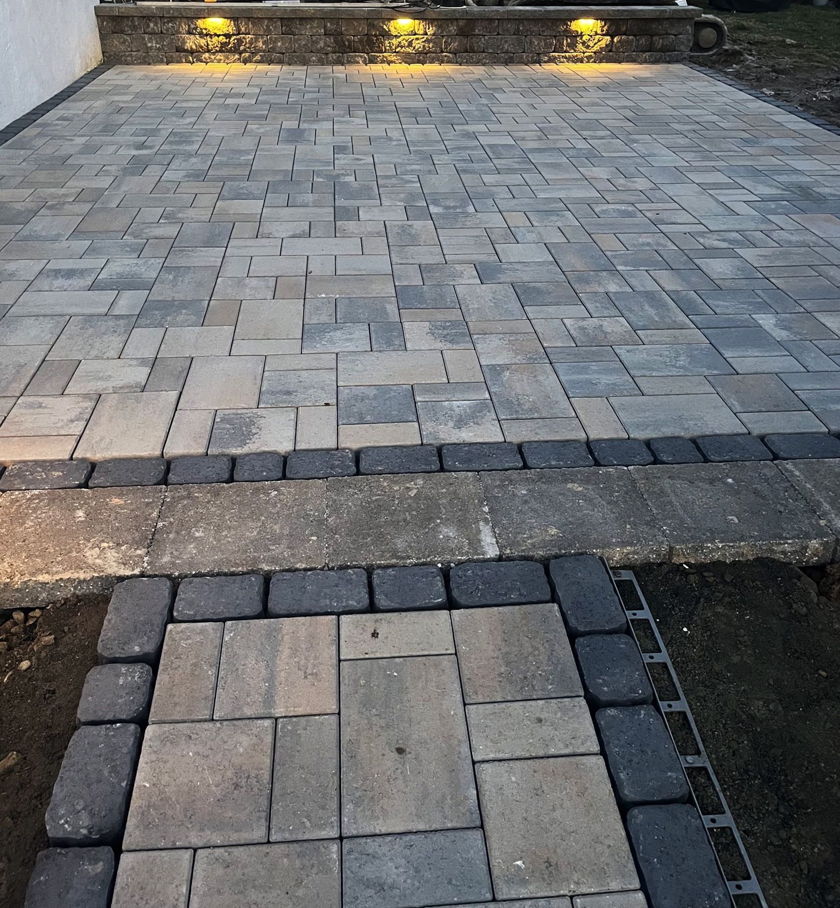 A brick walkway with lights on the side of it