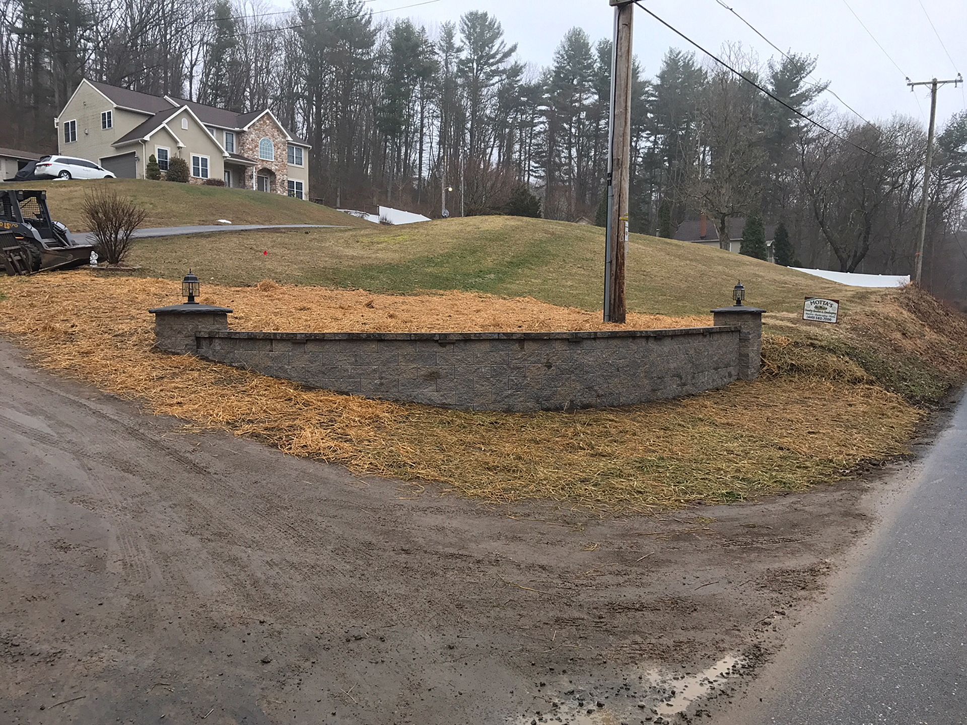 A dirt road with a stone wall on the side of it