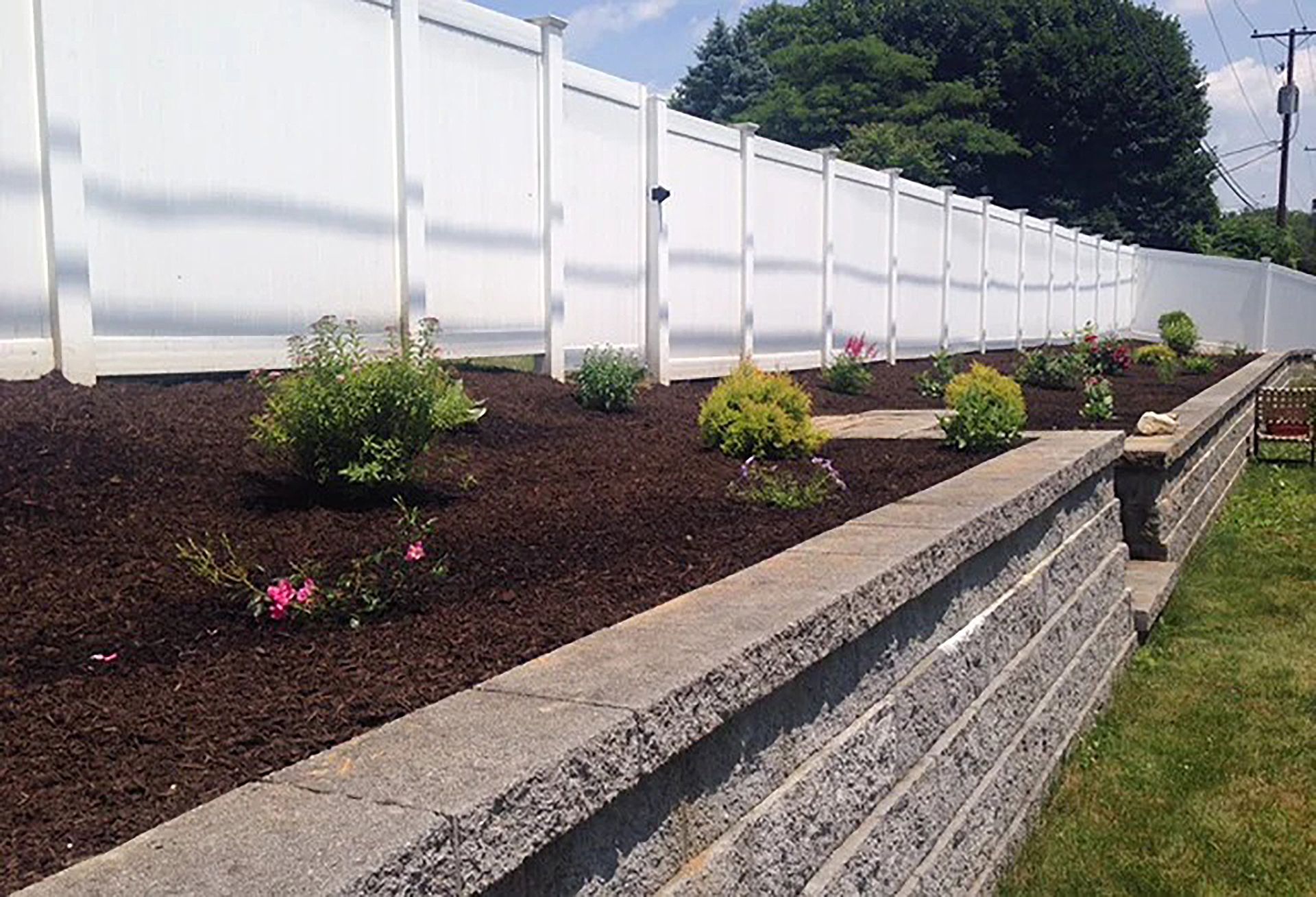 A white fence surrounds a lush green garden