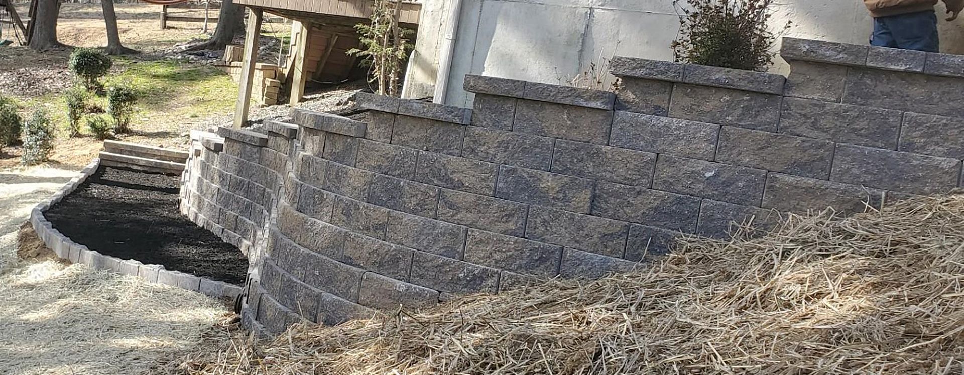 A brick wall is being built in the backyard of a house.