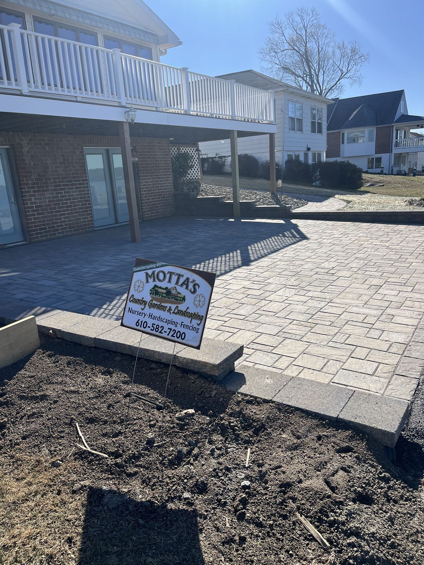 A sign is sitting in the dirt in front of a house.