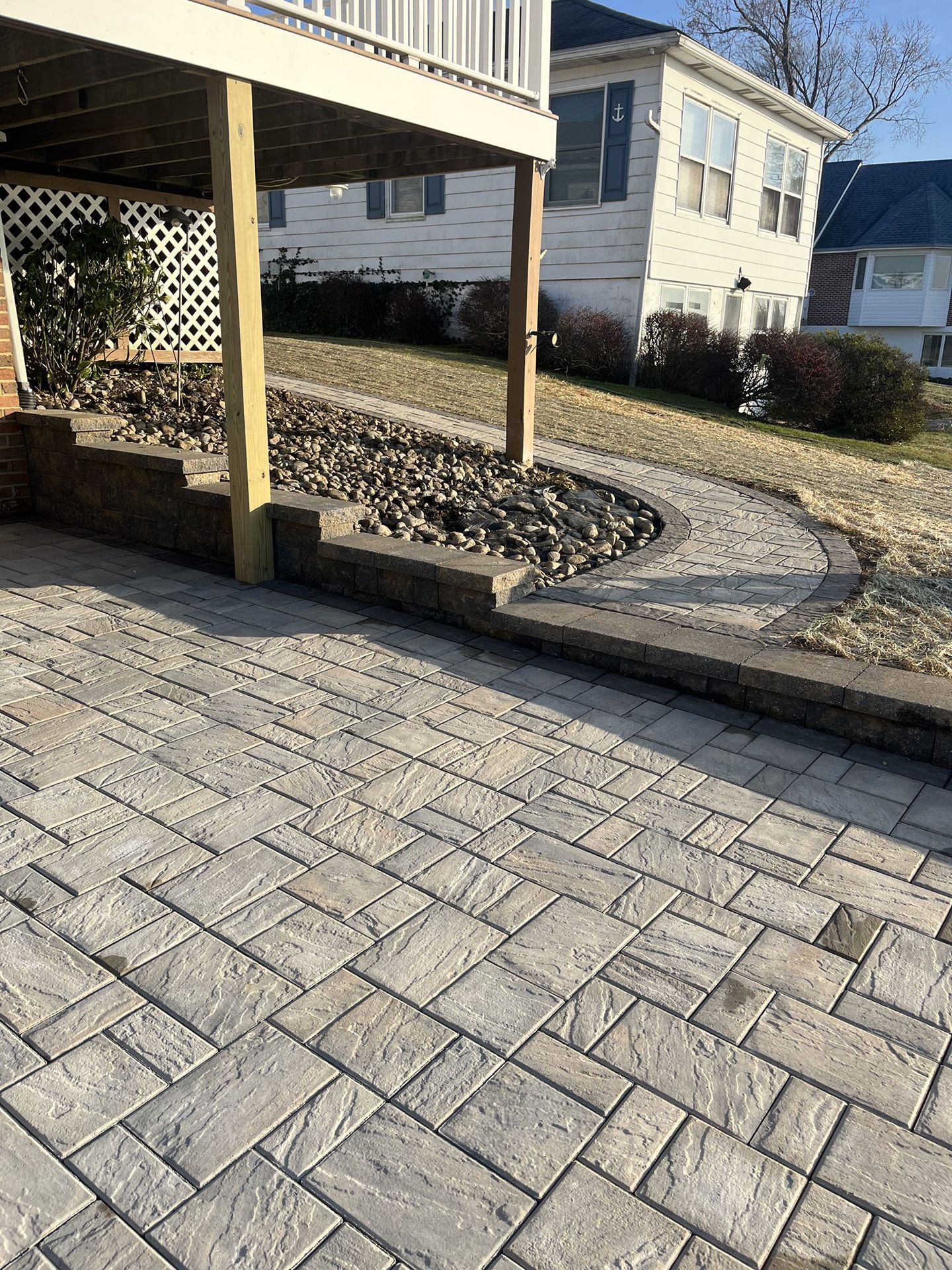 A patio with a deck and a house in the background.