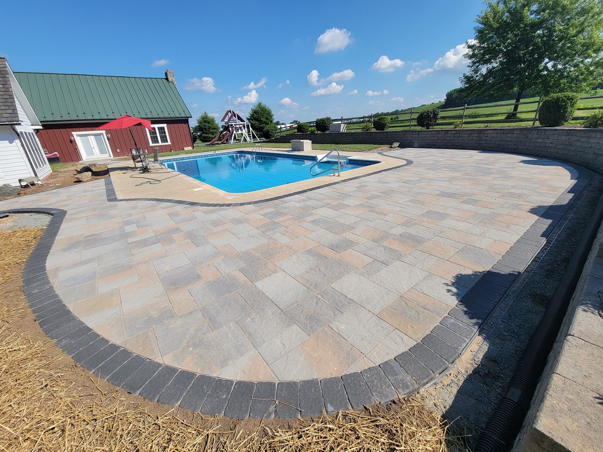 A large swimming pool is surrounded by a patio and a house.