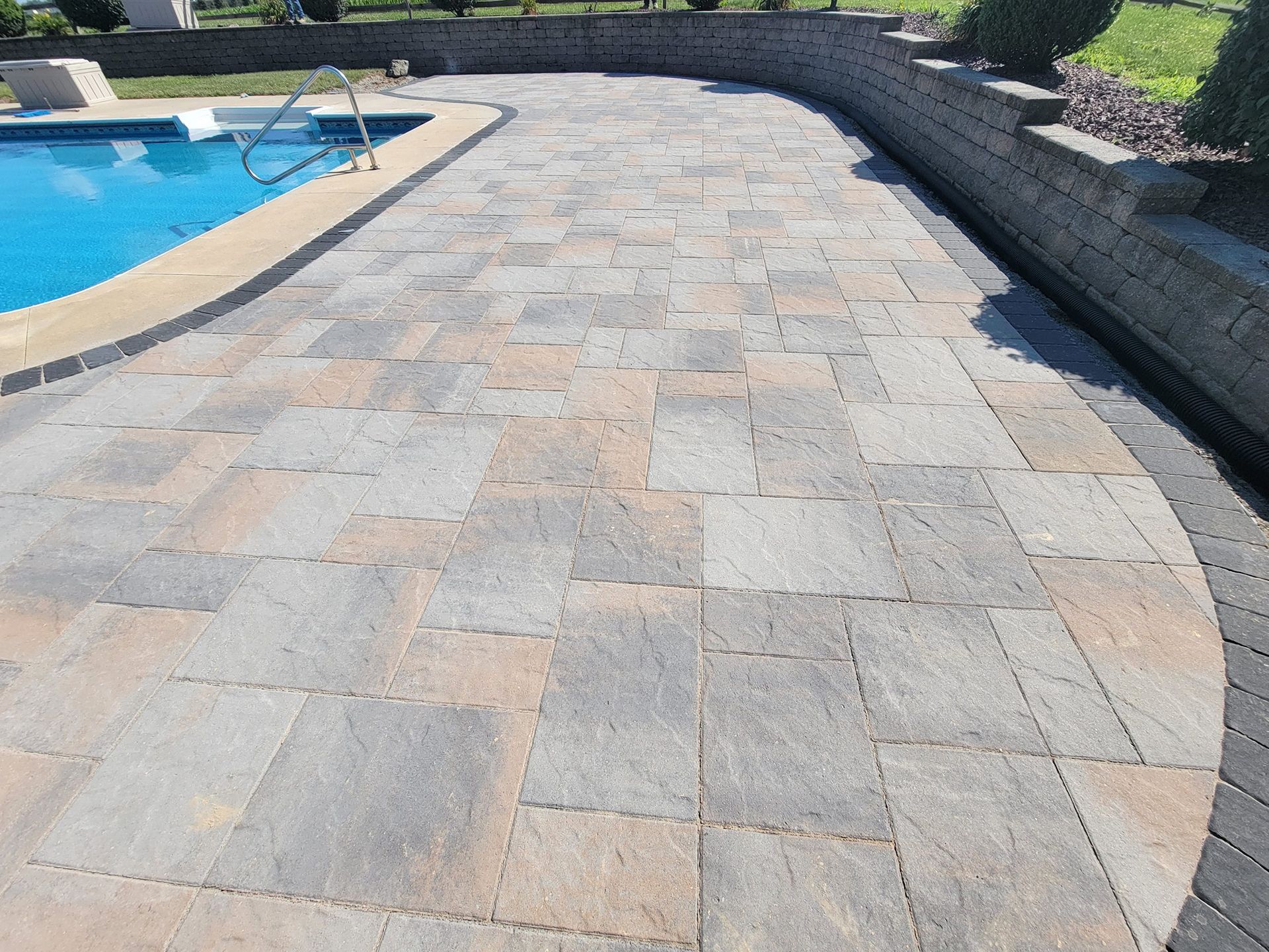 A patio with a swimming pool in the background