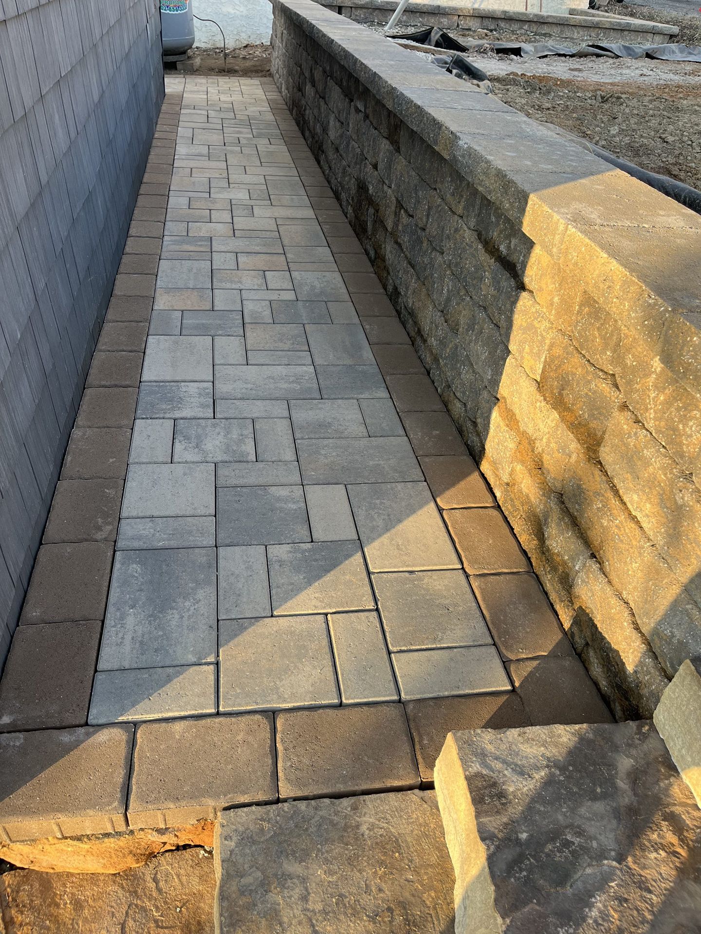 A brick walkway with a stone wall on the side of it