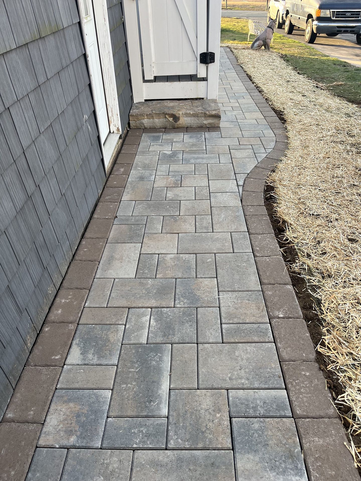 A walkway made of bricks is leading to a garage door.