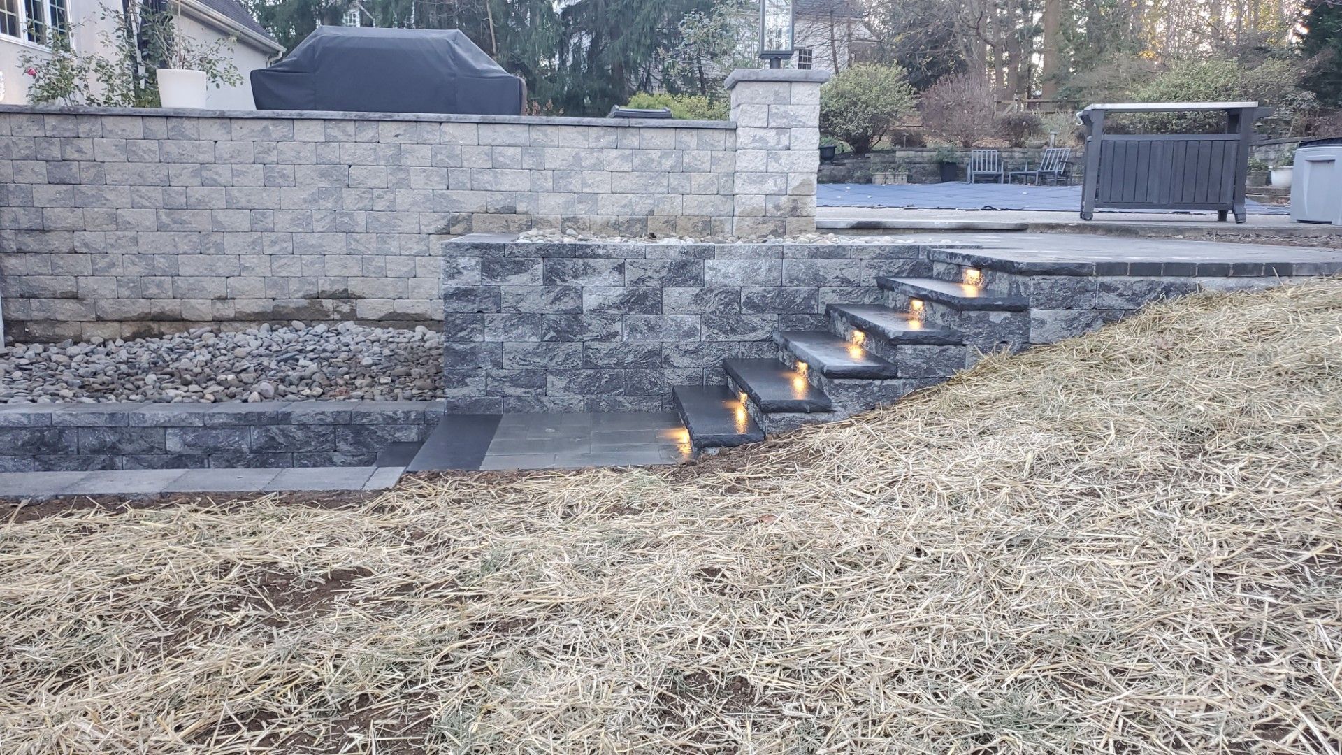 A brick wall with stairs leading up to it and a grill in the background.