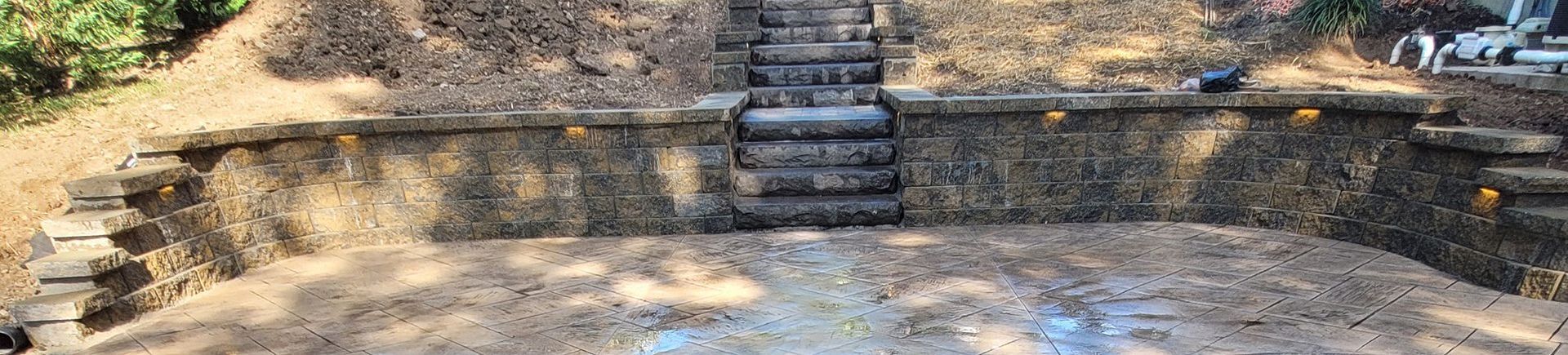 A stone wall with stairs leading up to it is surrounded by trees.