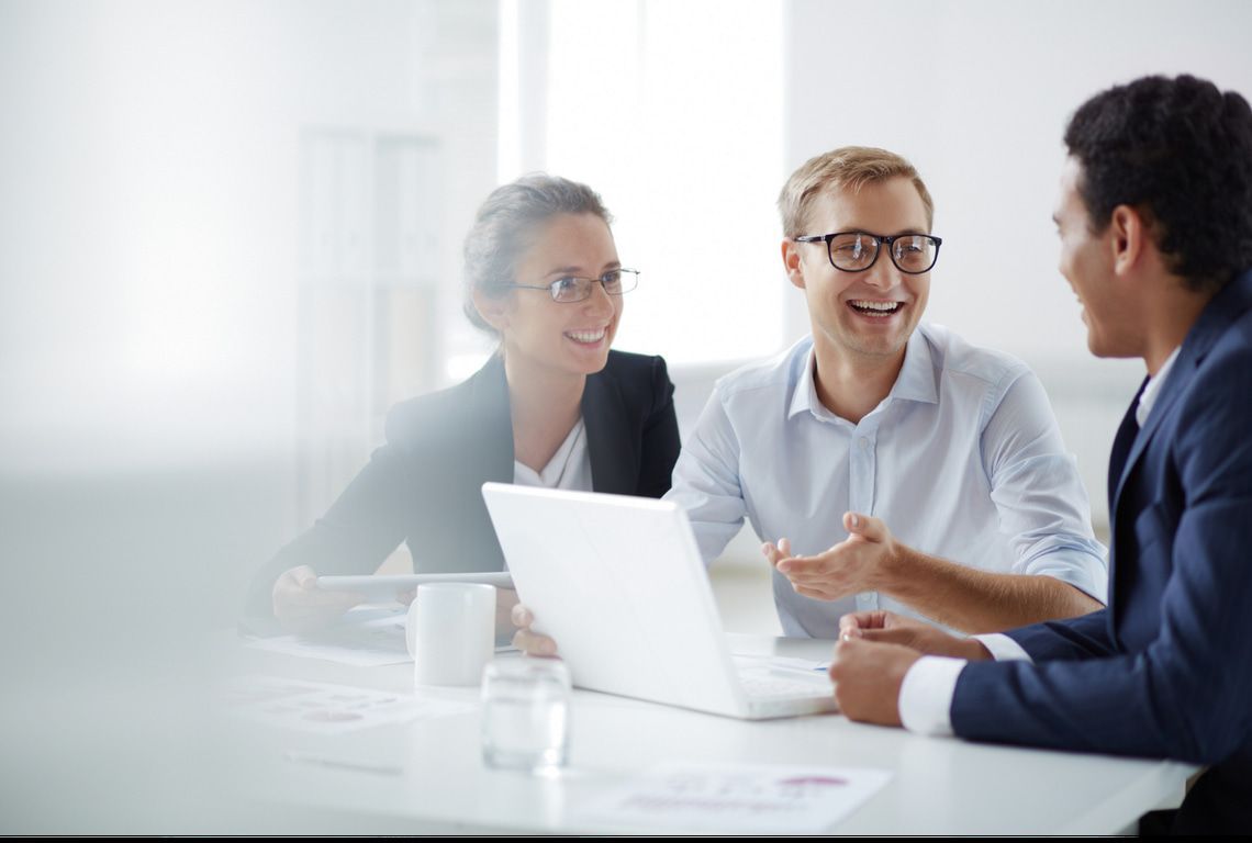 A group of people are sitting at a table with a laptop.
