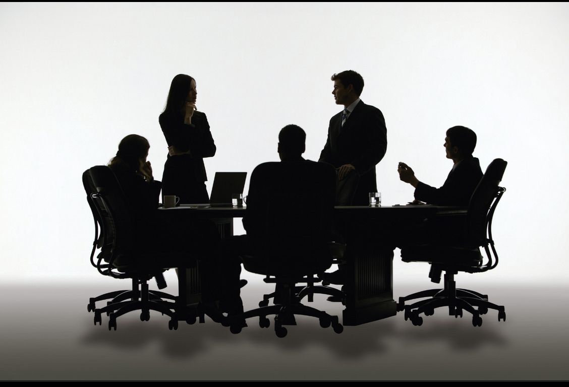 A group of people are sitting around a table having a meeting