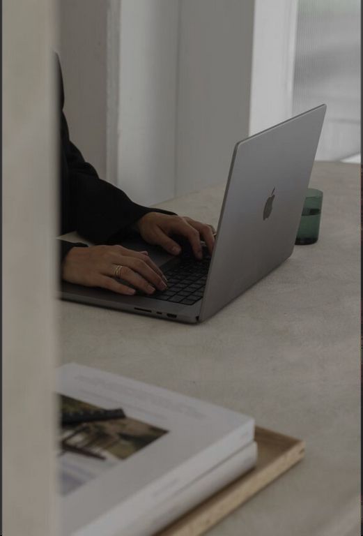 A person is typing on a laptop computer on a table.