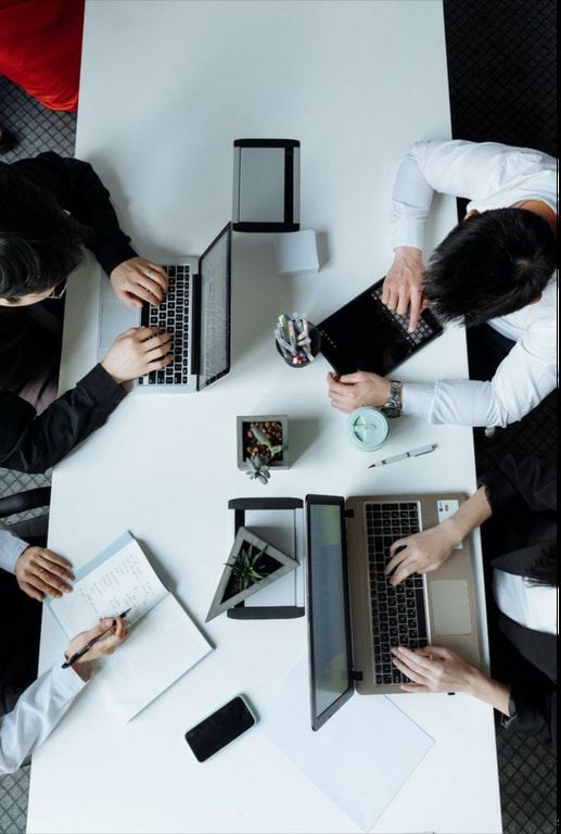 A group of people are sitting around a table using laptops