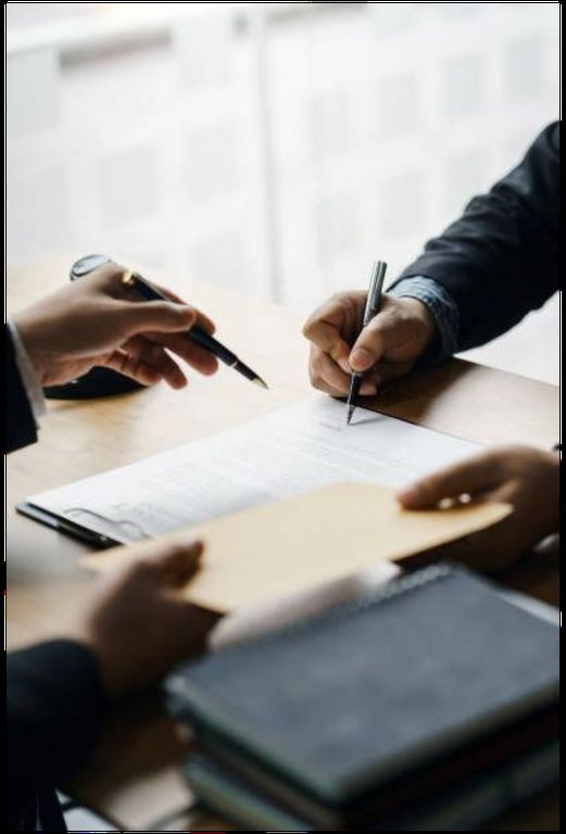 Two people are sitting at a table signing a document.