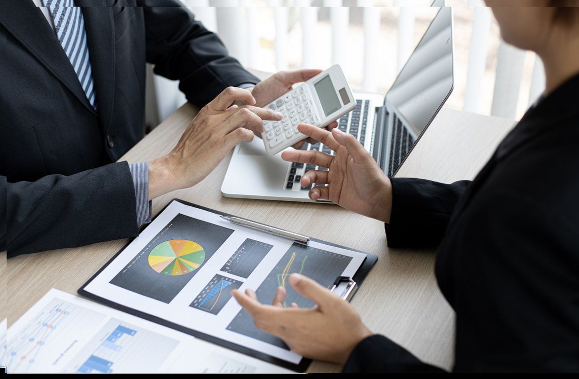 A man and a woman are sitting at a table with a laptop and a calculator.
