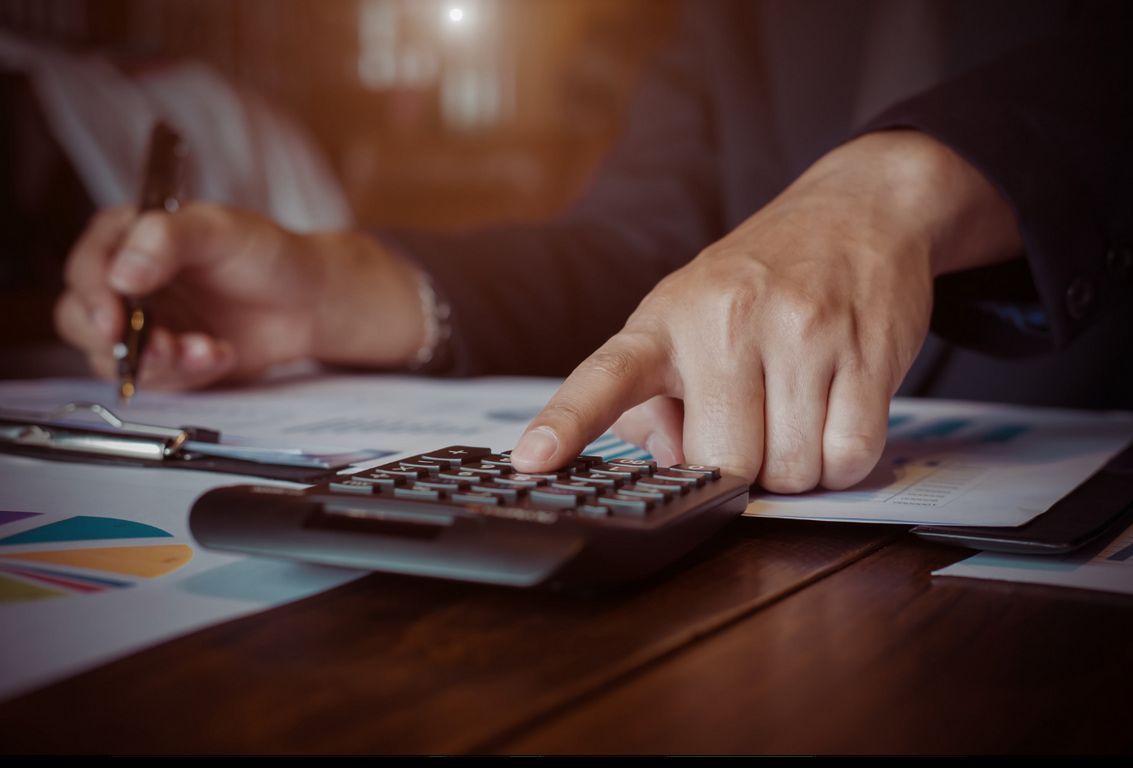 A person is using a calculator and writing on a piece of paper.