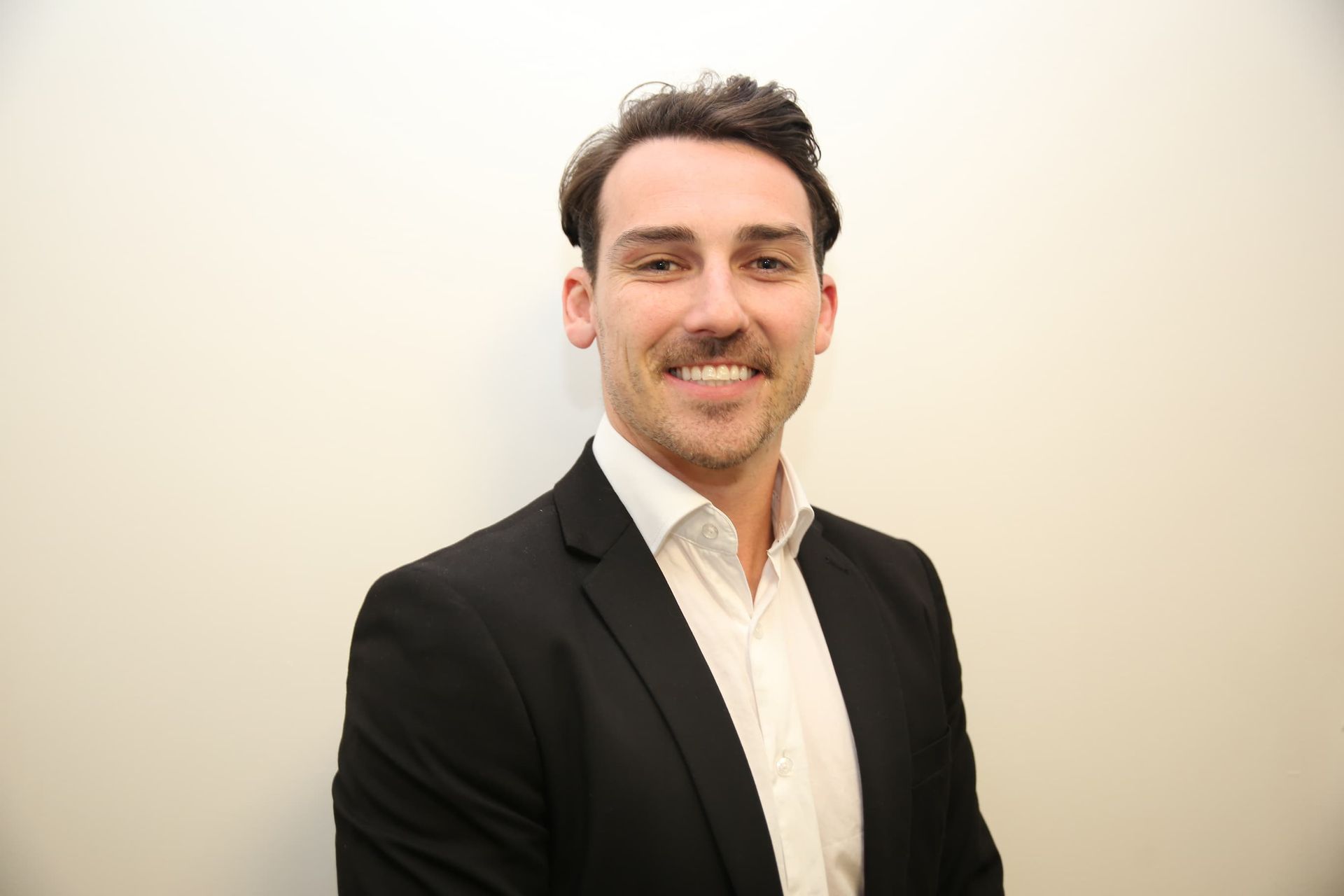 A man in a suit and white shirt is smiling for the camera.