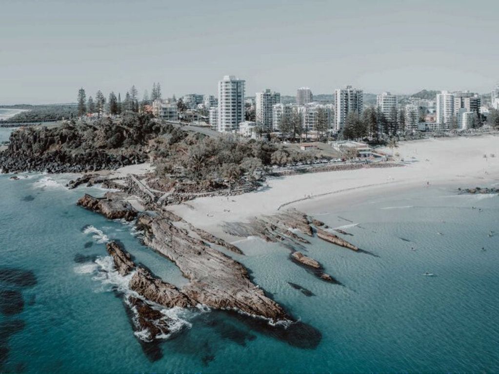An aerial view of a beach with a city in the background.