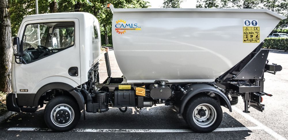 Camion della spazzatura bianco parcheggiato in strada, vista laterale con sollevatore idraulico e cassonetto compattatore posteriore.