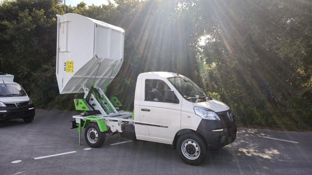 Mini camioncino bianco con cassone ribaltabile, parcheggiato all'aperto sotto il sole, con un'altra auto accanto.