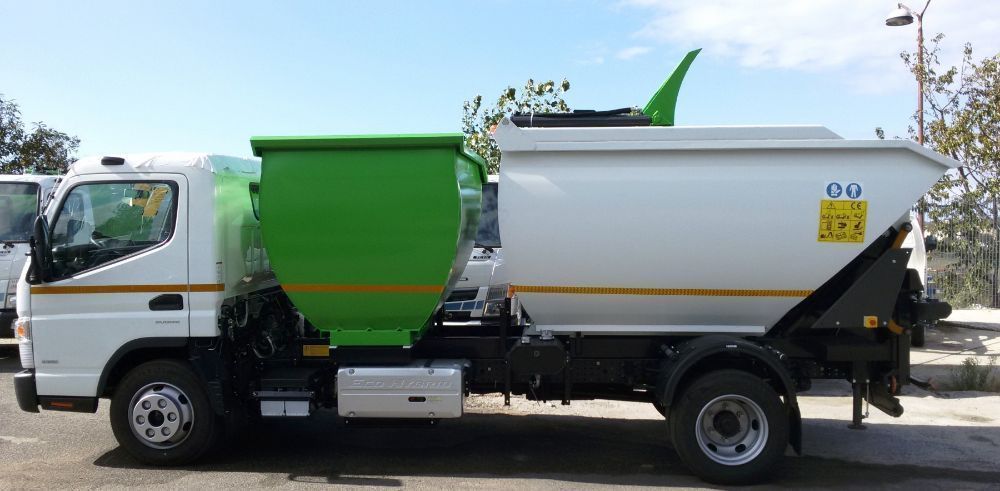 Camion della spazzatura bicolore bianco e verde parcheggiato su una strada all'aperto