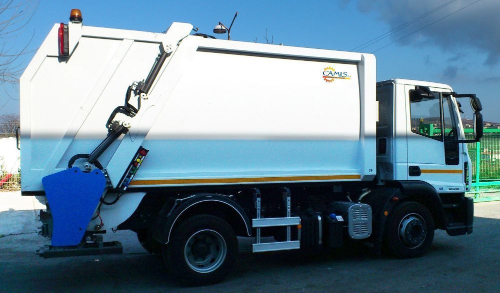 Camion della spazzatura bianco con attrezzatura blu, parcheggiato all'aperto sotto il sole.