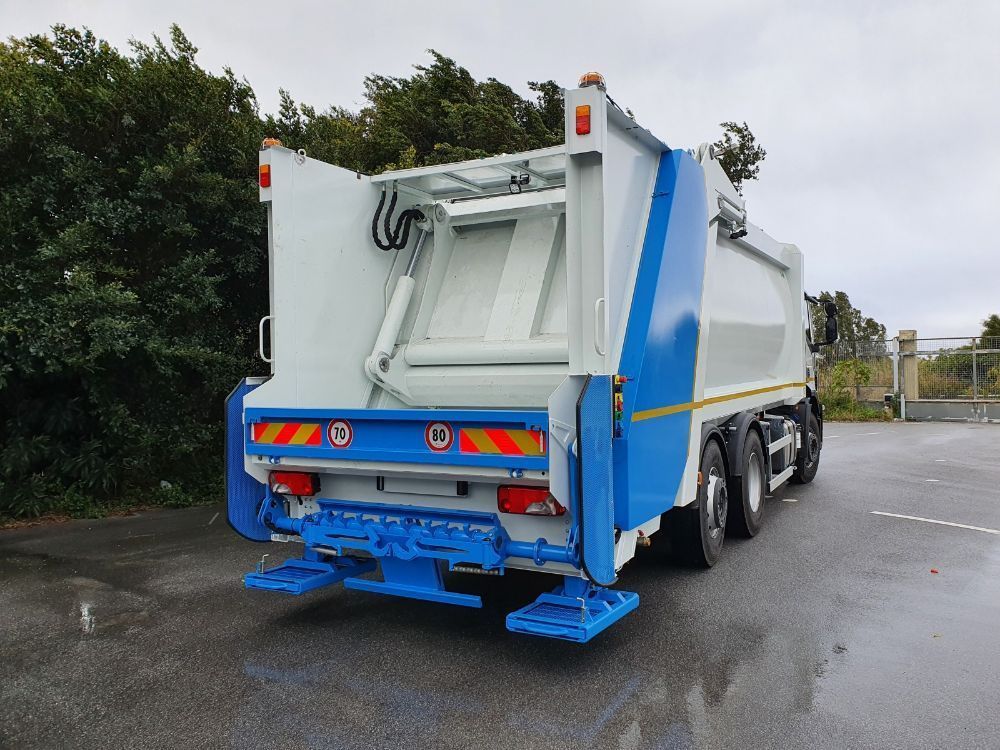 Vista posteriore di un camion della spazzatura bianco e blu parcheggiato su una strada.