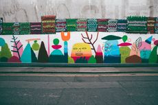 A wall with a lot of colorful paintings on it