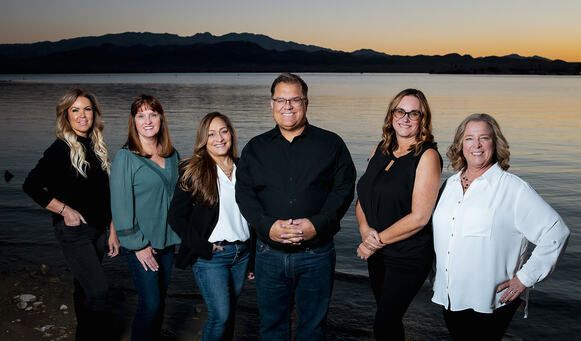 A group of women are posing for a picture in front of a lake.